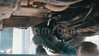 汽车服务-机械师在提升的汽车下工作时松开汽车部件